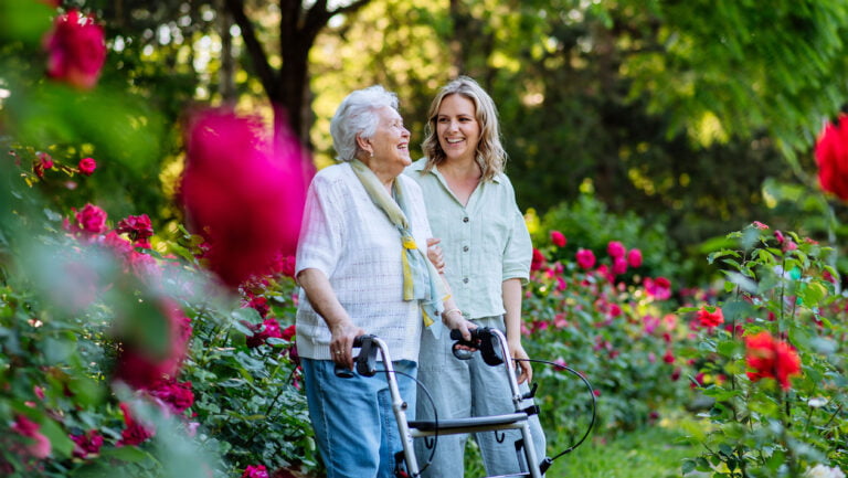 elderly woman at aged care facility in garden with adult grandchild